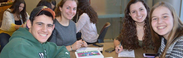 Teens writing purim cards for inclusion in the mishloach manot baskets 
